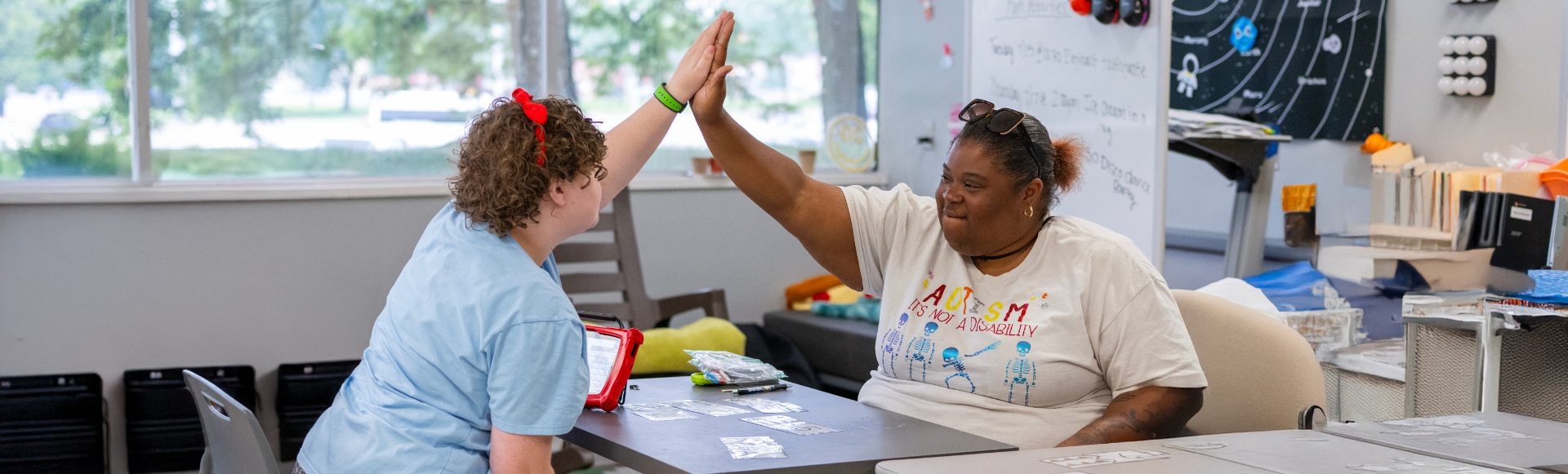 Two people giving a high five in a classroom setting