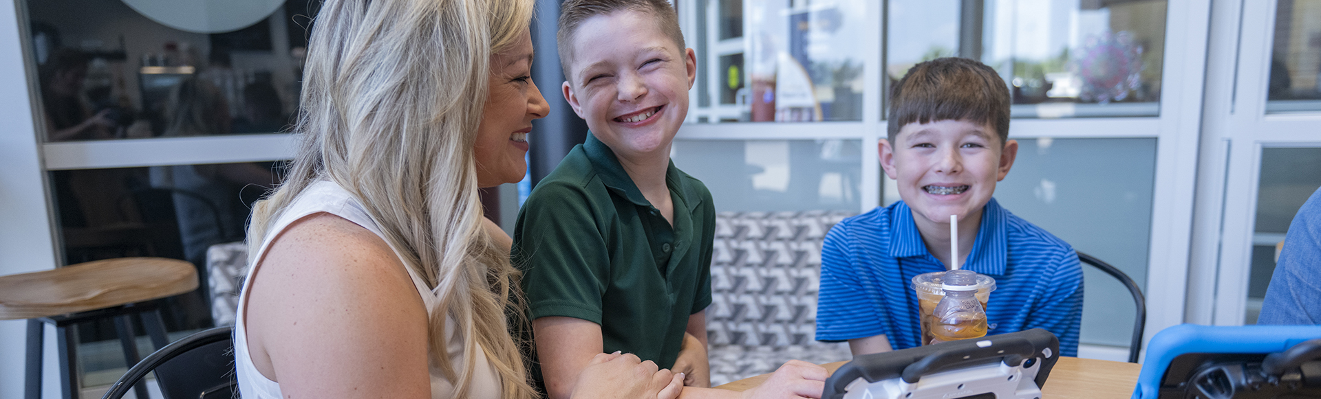 AAC Communicator smiling at a coffee shop with their family